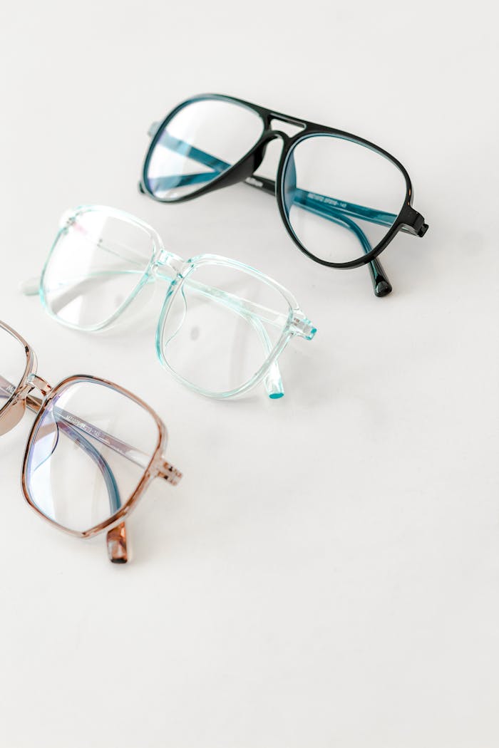 services-03 Three pairs of stylish eyeglasses arranged on a white surface, showcasing different frame colors and styles.